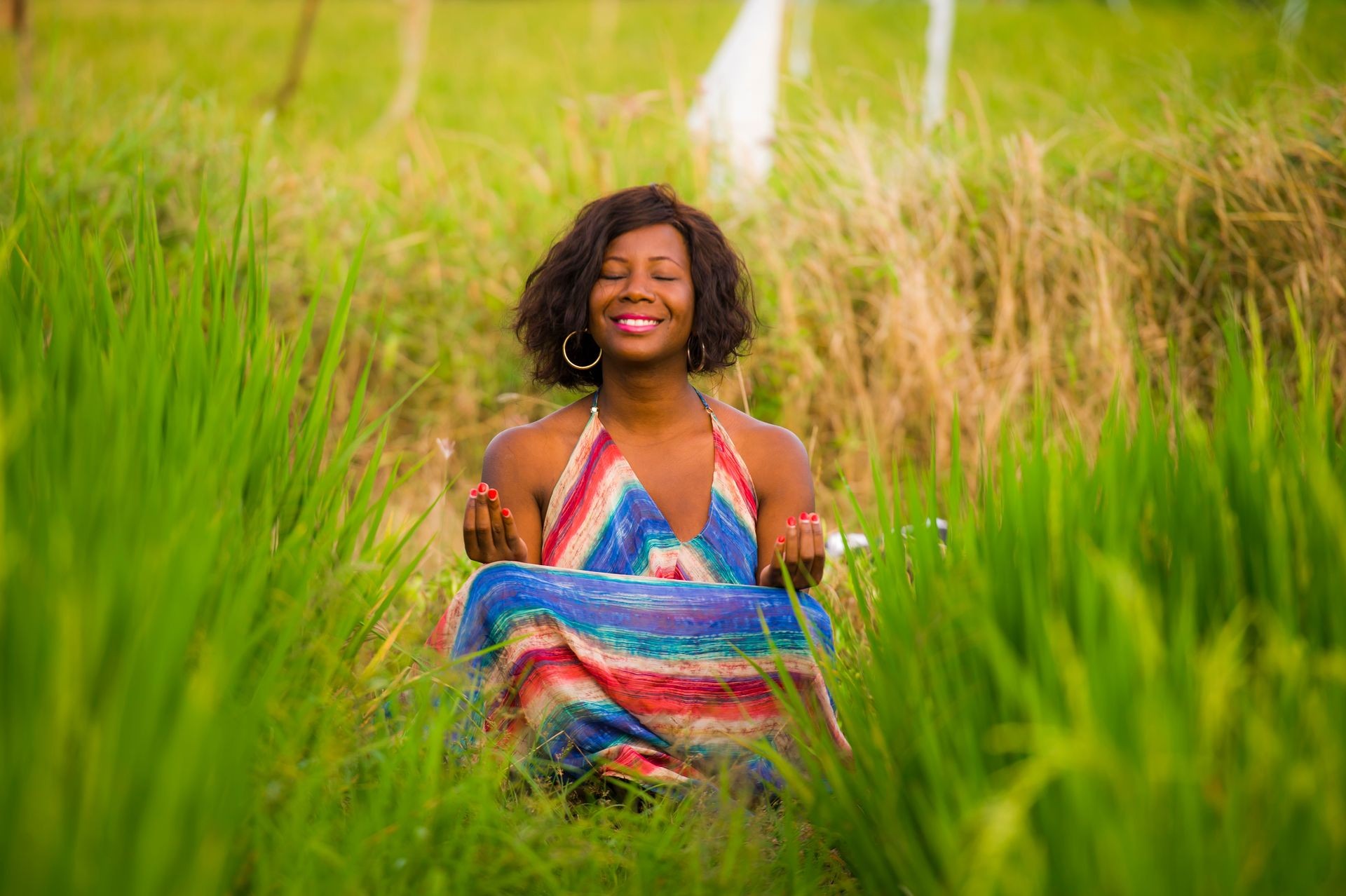 young beautiful and happy black afro American woman sitting at rive field outdoors practicing yoga relaxation and meditation enjoying holidays at tropical destination smiling cheerful